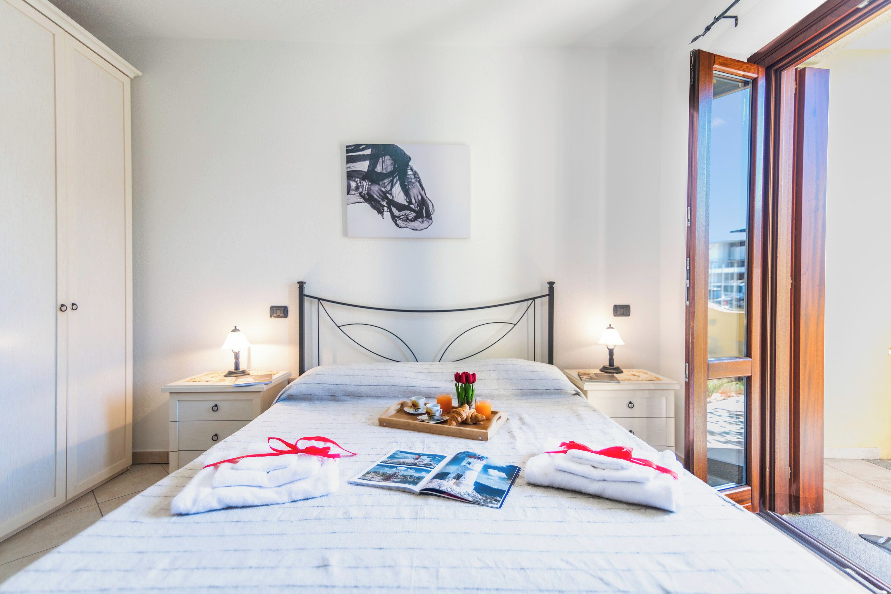 Un lit bien fait, avec un plateau de petit-déjeuner, un magazine et des serviettes.