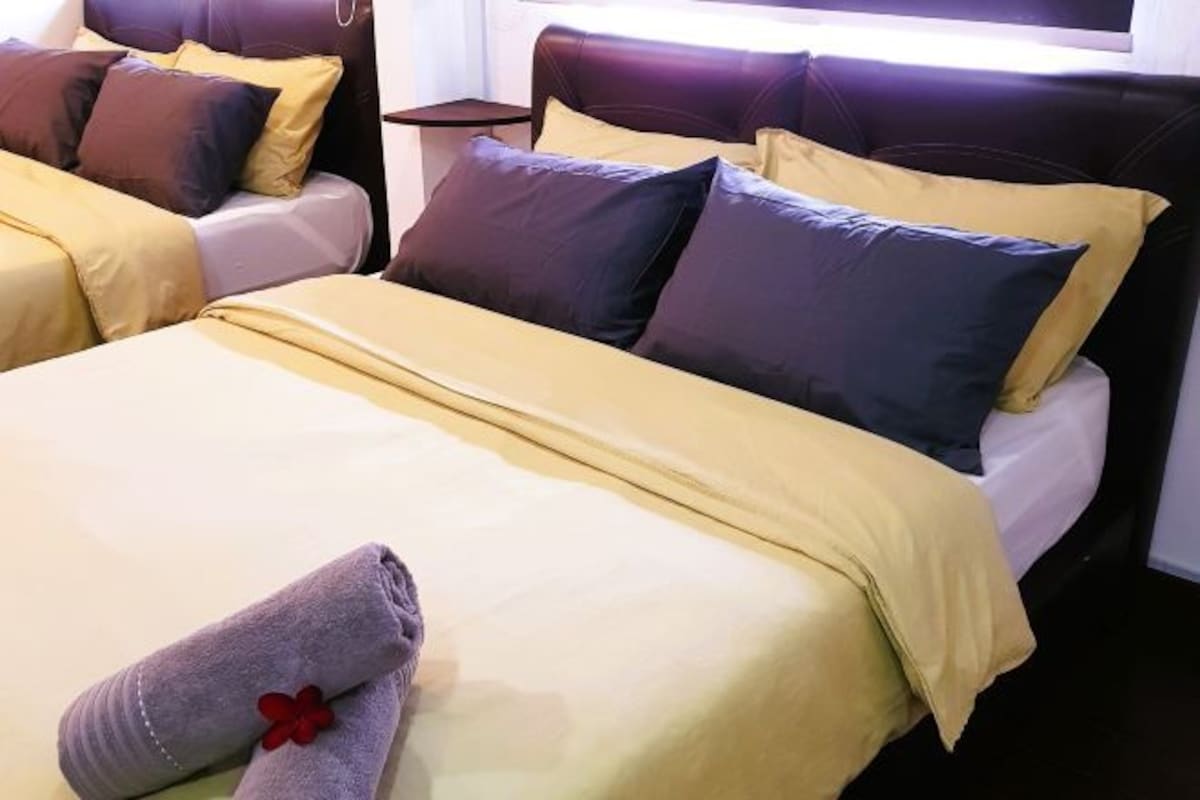 Ein Hotelzimmer mit zwei Betten, jeweils mit Kopfteil und mehreren Kissen.