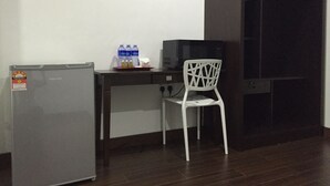 A kitchenette with a refrigerator, microwave, and cabinet. There is a chair and a tray with bottled water and condiments. - Cassa Kaseh Guest House (Langkawi)