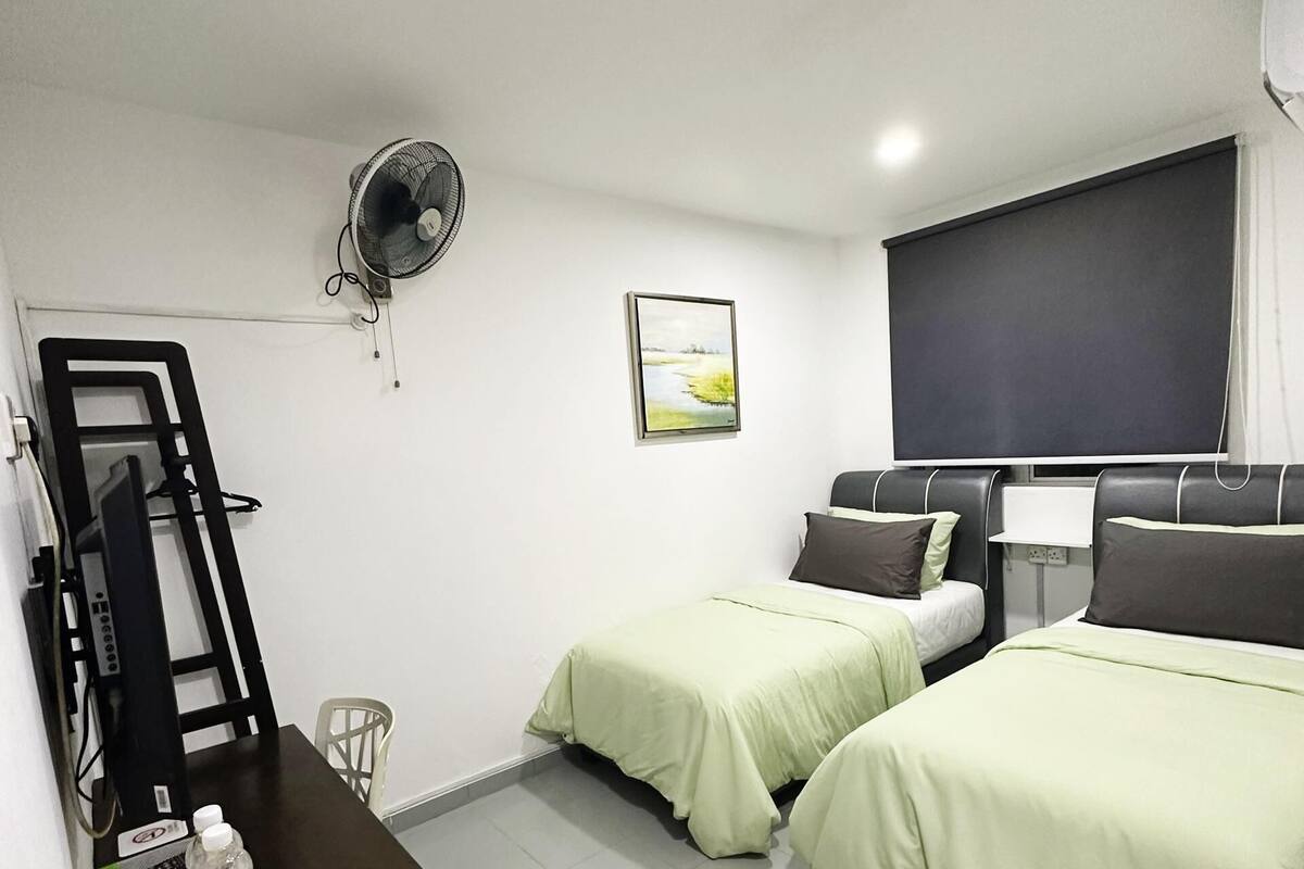 Habitación de hotel con dos camas, un escritorio, una silla, un ventilador, un cuadro y un ventanal grande.