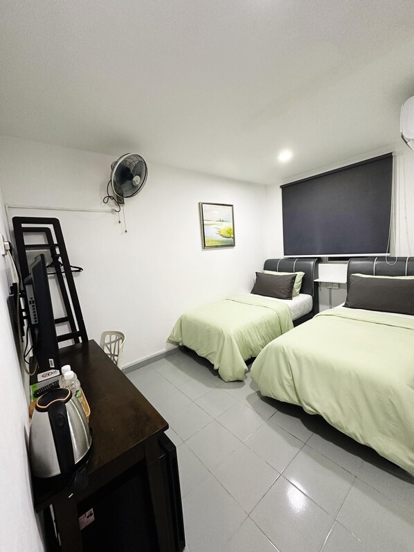 Habitación de hotel con dos camas, un escritorio, una silla, un ventilador, un cuadro y un ventanal grande.