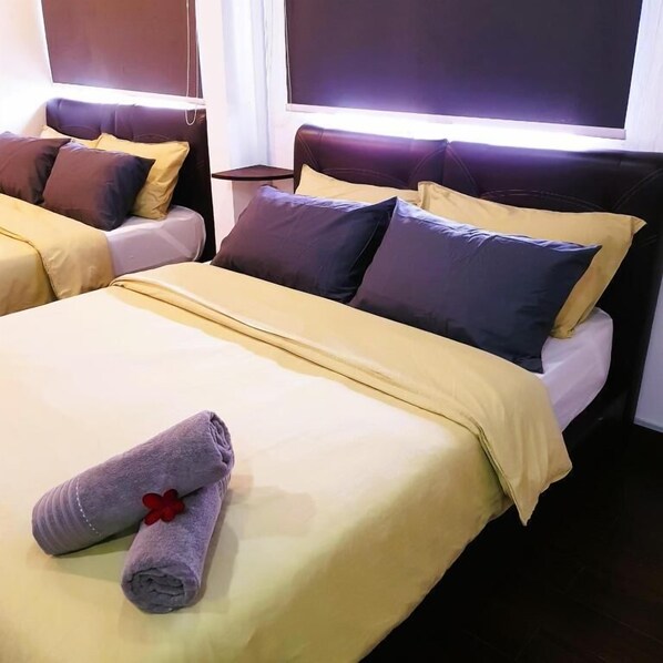 A hotel room with two beds, each with a headboard, a bedside table, and a window.