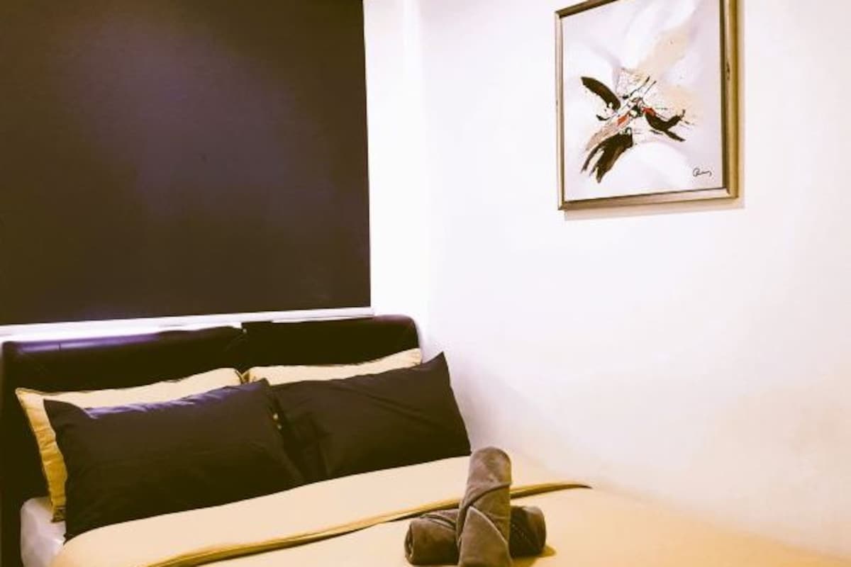 Ein Schlafzimmer mit einem Bett, Kissen und einem gerahmten Kunstwerk an der Wand.