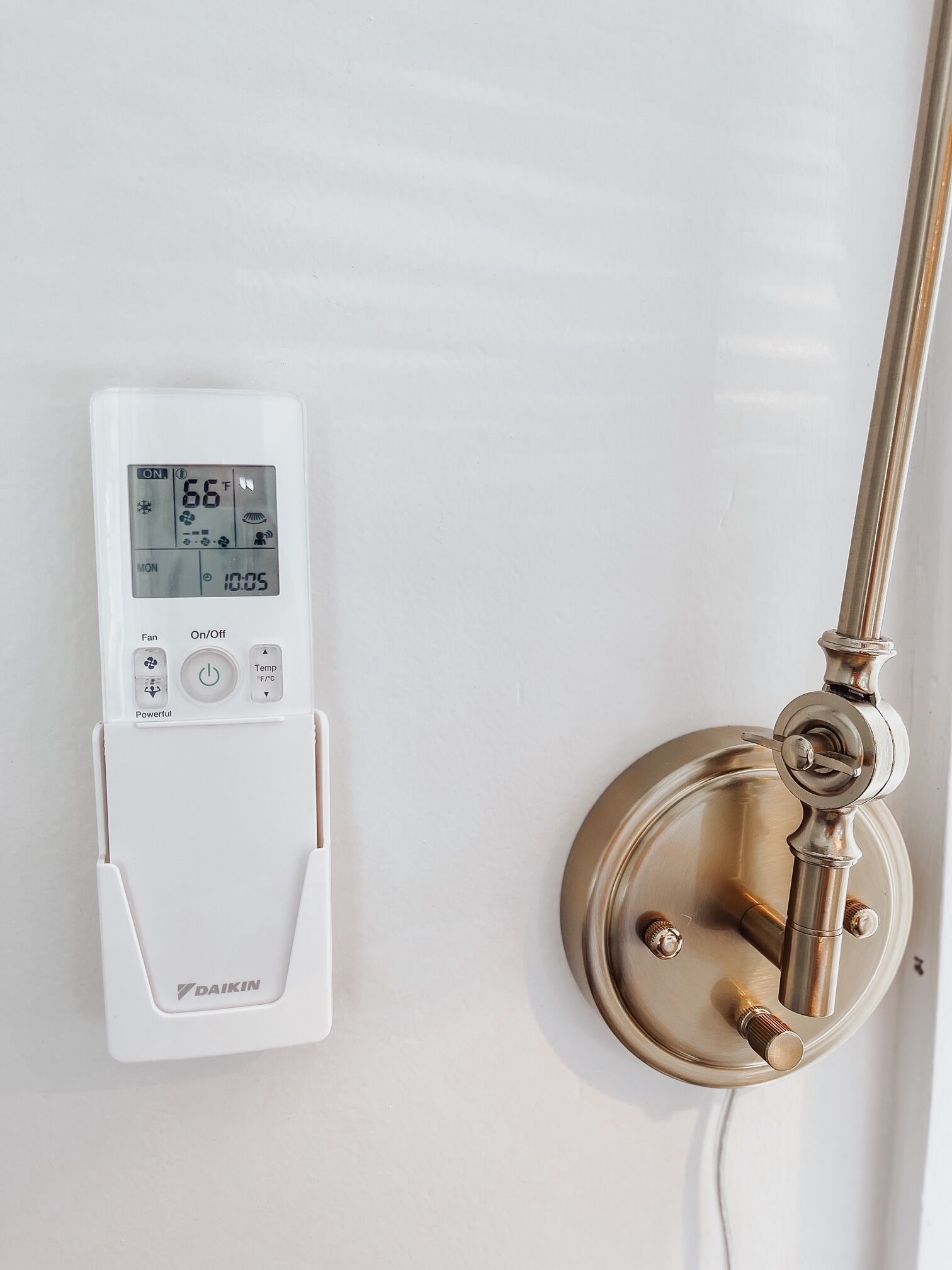 A thermostat and a brass faucet on a wall.