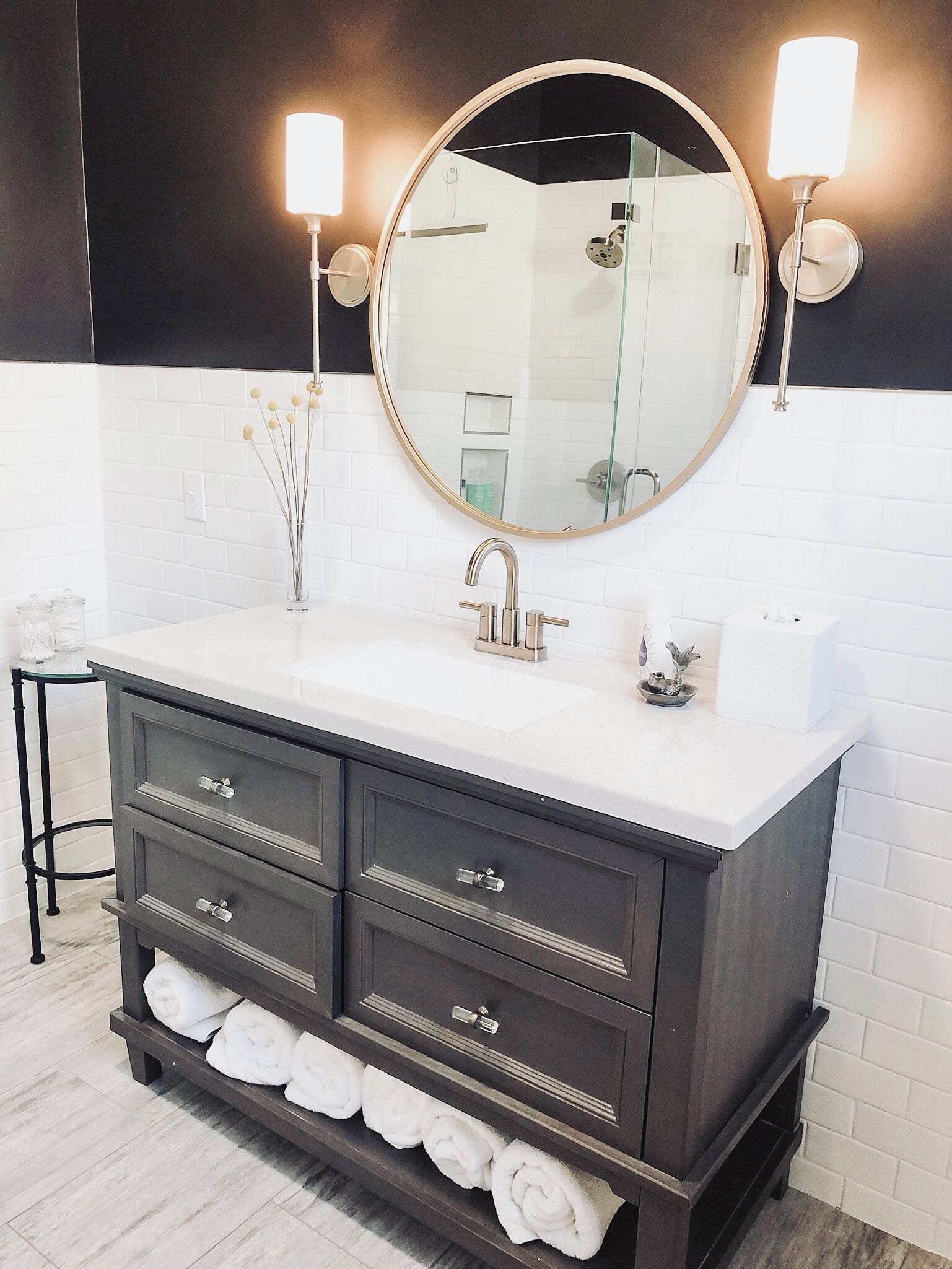 A modern bathroom with a dark wooden vanity, white countertop, and a large mirror.