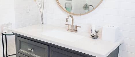 A modern bathroom with a dark wooden vanity, white countertop, and a large mirror.