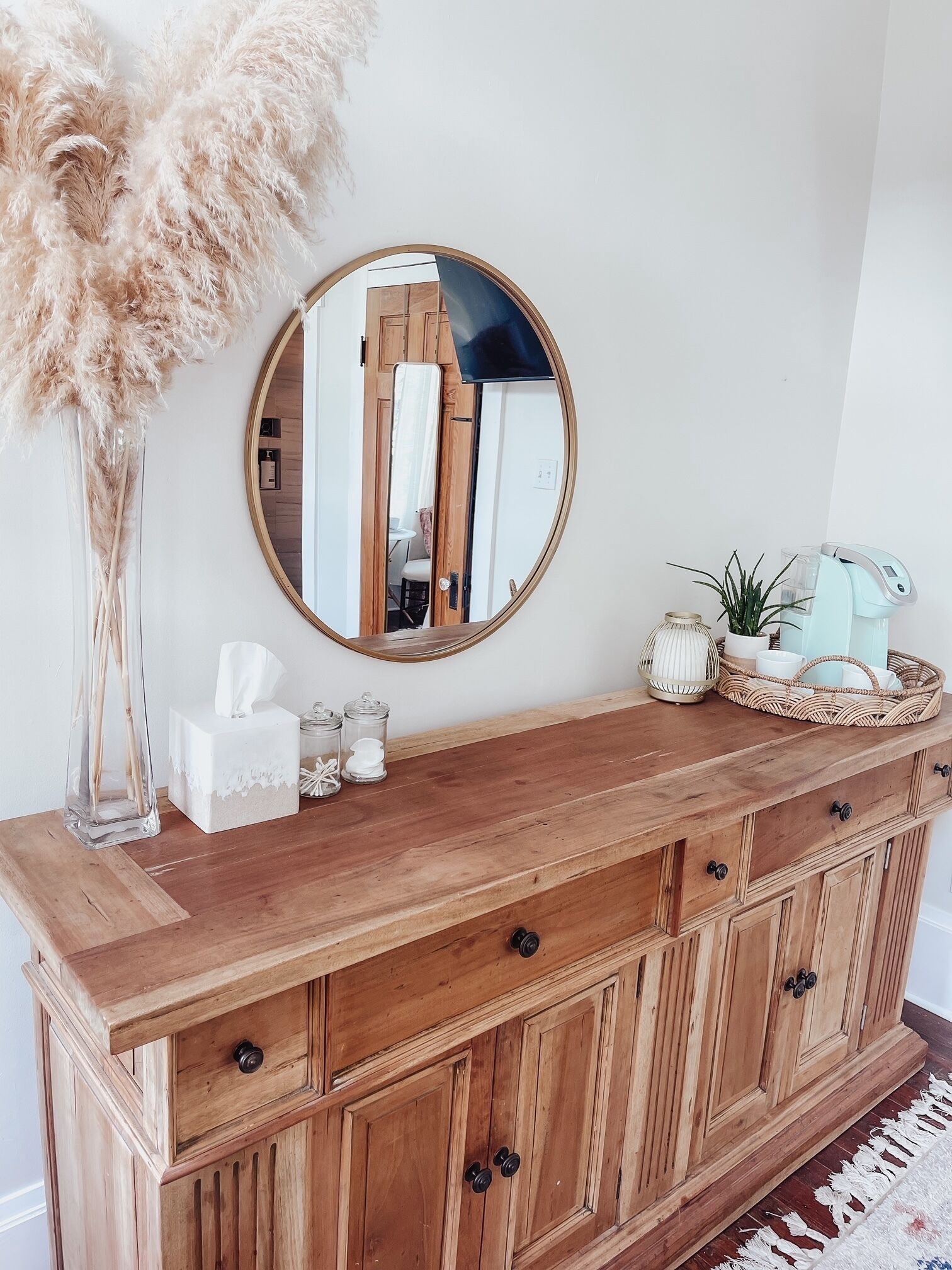 A wooden vanity with a round mirror, a tissue box, and decorative items.