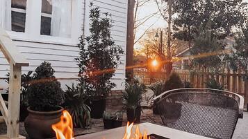 A patio with a fire feature, potted plants, and a chair.
