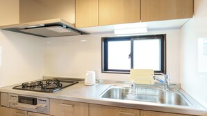 A kitchen with a gas stove, a built-in oven, a sink with a dish rack, and wooden cabinets.