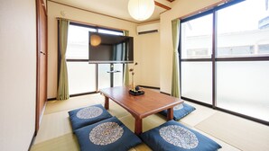 A traditional Japanese room with tatami flooring, a low table, and cushions with circular patterns.