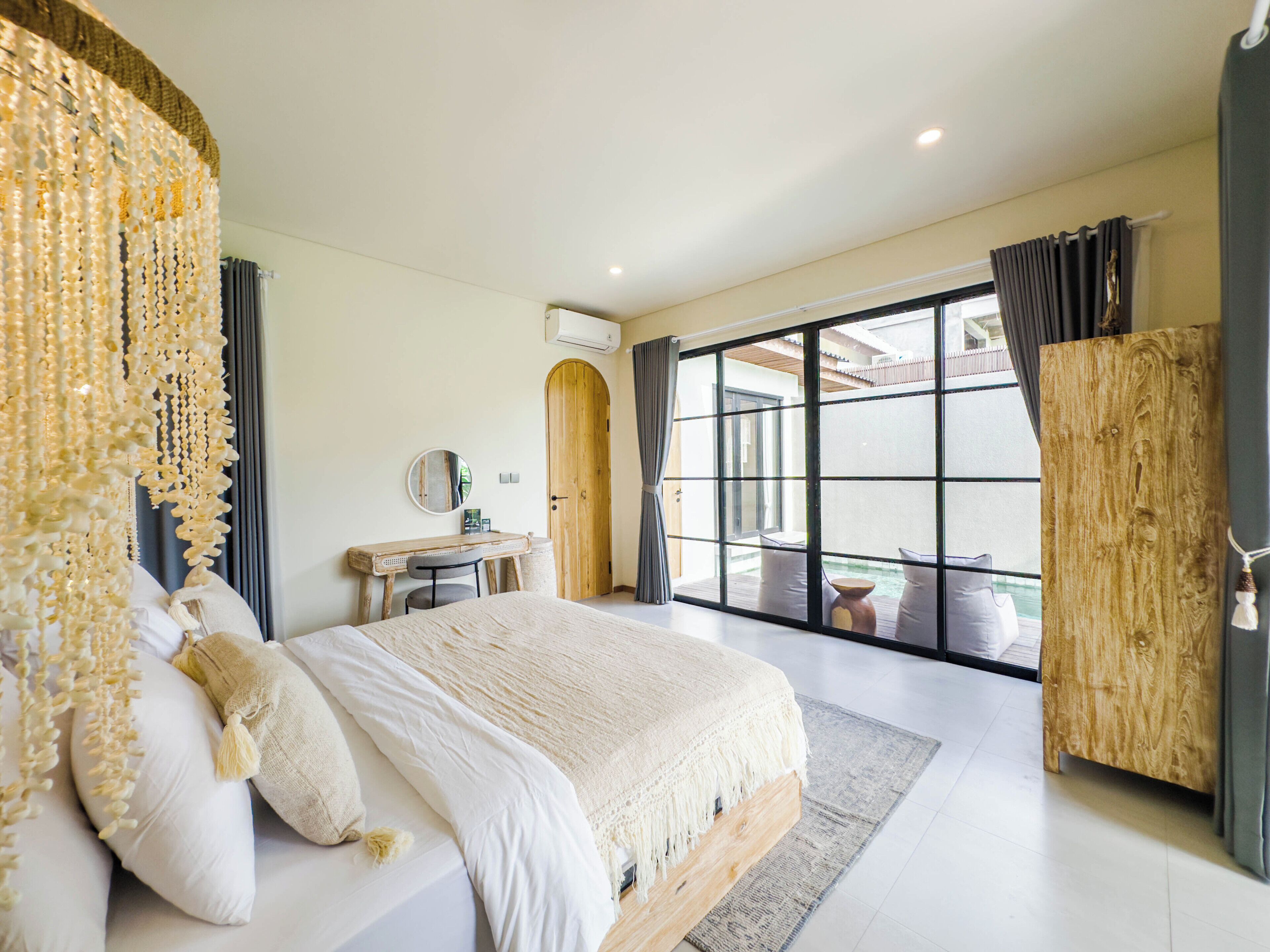 A bedroom with a large bed, a desk, and a view of an outdoor area.