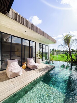A modern house with a swimming pool, large windows, and a wooden deck. - Nasha Stana Ricefields View (Ubud)