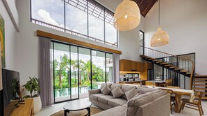 A spacious living area with a large sofa, a dining table, and a kitchen in the background.