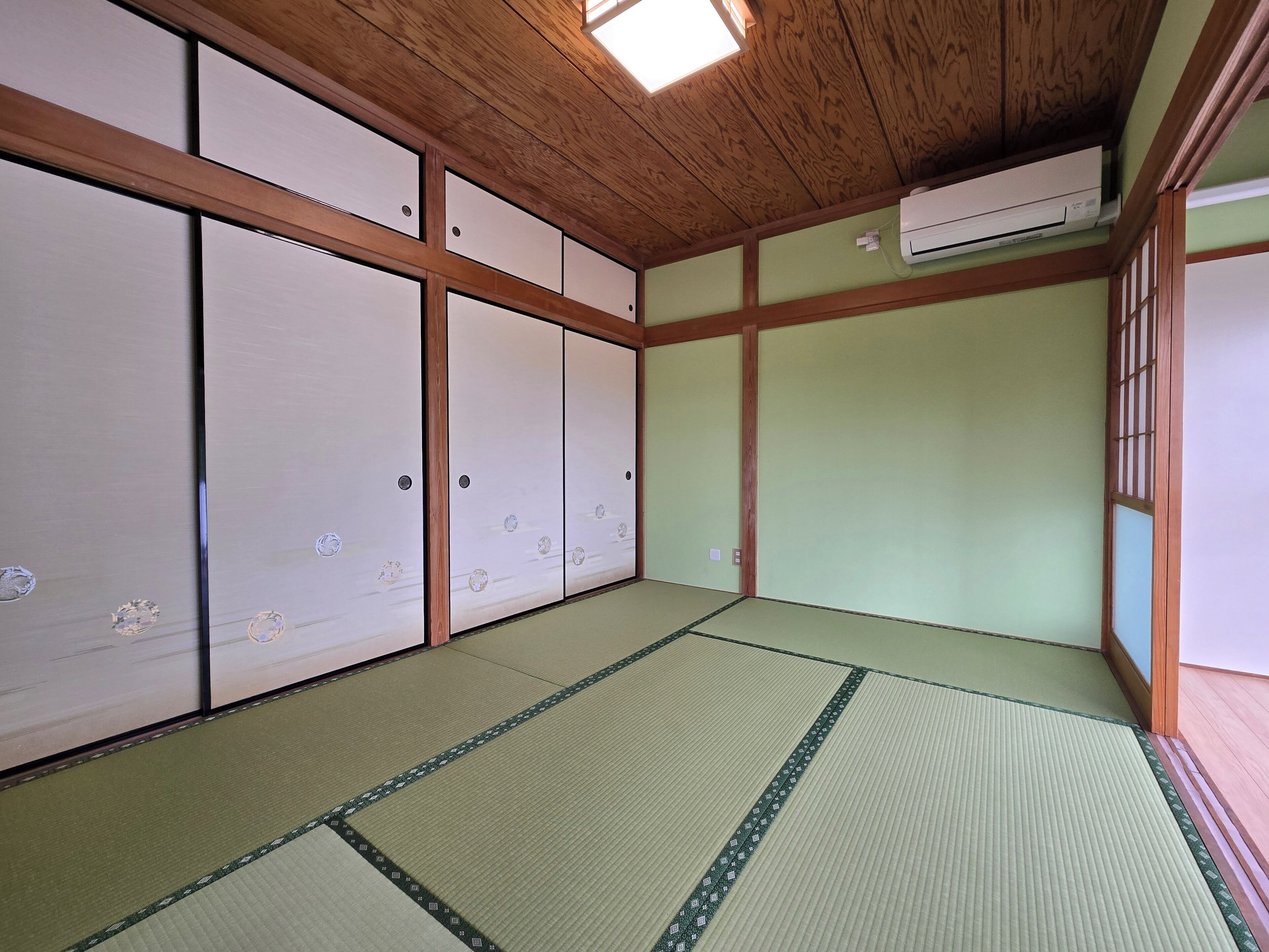 Una habitación japonesa tradicional con suelo de tatami, puertas correderas y un ventilador de techo.