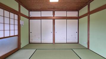 A traditional Japanese room with tatami flooring, sliding shoji doors, and a wooden ceiling.