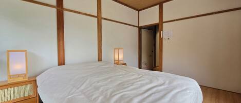 A bedroom with a large bed, wooden headboard, bedside tables with lamps, and a wooden ceiling.