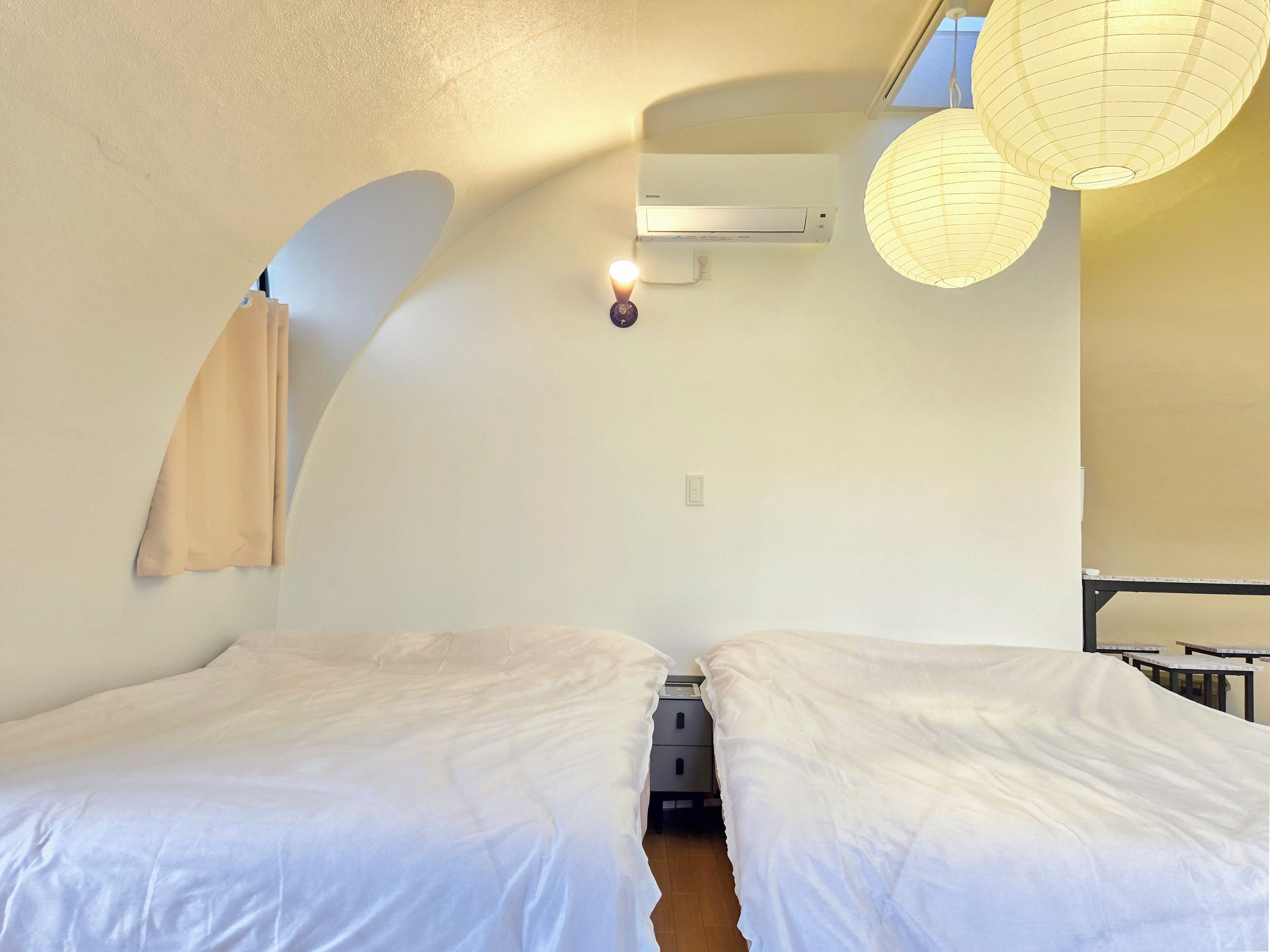 Una camera da letto con due letti, una ventola a soffitto e un condizionatore d'aria a parete.