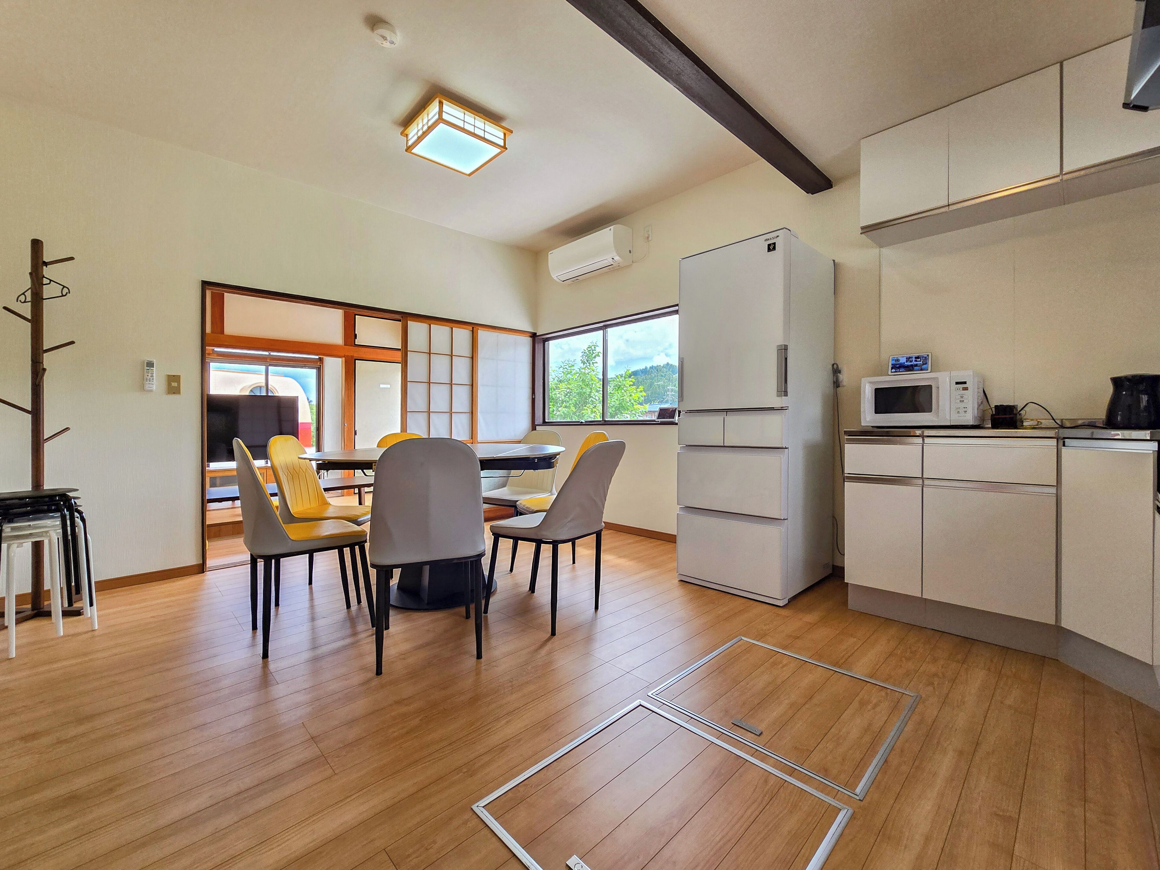 Eine moderne Küche mit Kühlschrank, Mikrowelle und einem Essbereich mit Stühlen und Tisch.