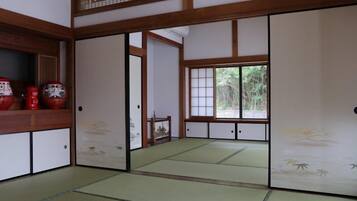 Una habitación japonesa tradicional con suelo de tatami, puertas correderas y vistas al verdor exterior.