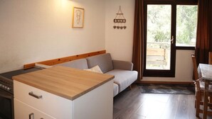 A compact kitchen with a wooden countertop and white cabinets, a grey sofa, and a dining area with a table and chairs. - Nice studio 6 persons COEUR DE STATION (LES ORRES 1650)