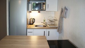 A kitchen with a microwave, sink, kettle, and a stove. - Nice studio 6 persons COEUR DE STATION (LES ORRES 1650)