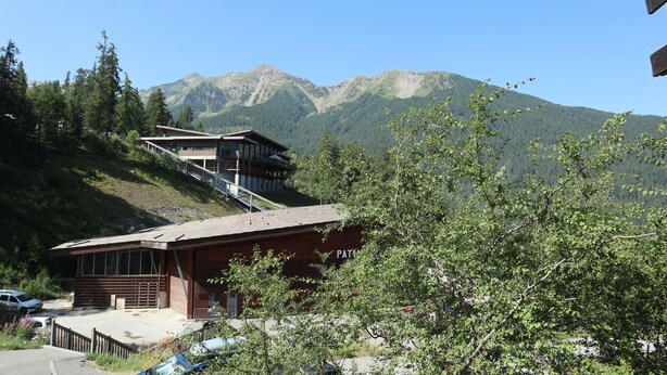 A mountain lodge with a wooden exterior, a covered outdoor seating area, and a view of the surrounding mountains. - Nice studio 6 persons COEUR DE STATION (LES ORRES 1650)