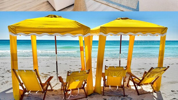 Un salón moderno con un amplio ventanal con vista al mar, un sofá blanco y un cuadro de una concha.