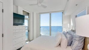 Un dormitorio con una cama grande, un televisor en una cómoda y vistas al océano.