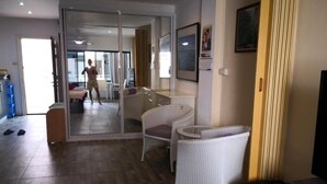 A hotel room with a sliding glass door leading to a balcony, a white wicker chair, a small table, and a television. - Room-jomtien Hill Resort Pratamnak 315 (Pattaya)