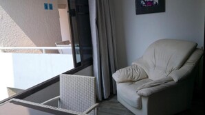 A balcony with a wicker chair, a beige sofa, and a glass table. - Room-jomtien Hill Resort Pratamnak 315 (Pattaya)