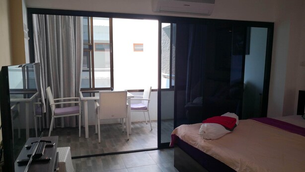 A hotel room with a bed, a desk with two chairs, a television, and an air conditioning unit. - Room-jomtien Hill Resort Pratamnak 315 (Pattaya)