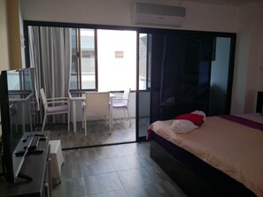 A hotel room with a bed, a desk with two chairs, a television, and an air conditioning unit. - Room-jomtien Hill Resort Pratamnak 315 (Pattaya)