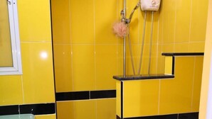 A bathroom with yellow tiles, a white toilet, and a shower with a soap dispenser. - Room-jomtien Hill Resort Pratamnak 315 (Pattaya)