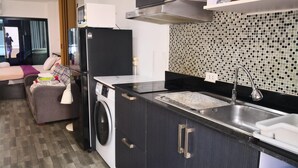 A compact kitchen with a washing machine, a microwave, and a sink. - Room-jomtien Hill Resort Pratamnak 315 (Pattaya)