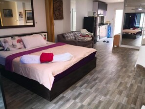 Relax in a spacious room with a large bed, sofa, and kitchen area.