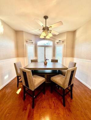 Cozy dining area with a round table and four comfortable chairs, complete with a ceiling fan and natural light.