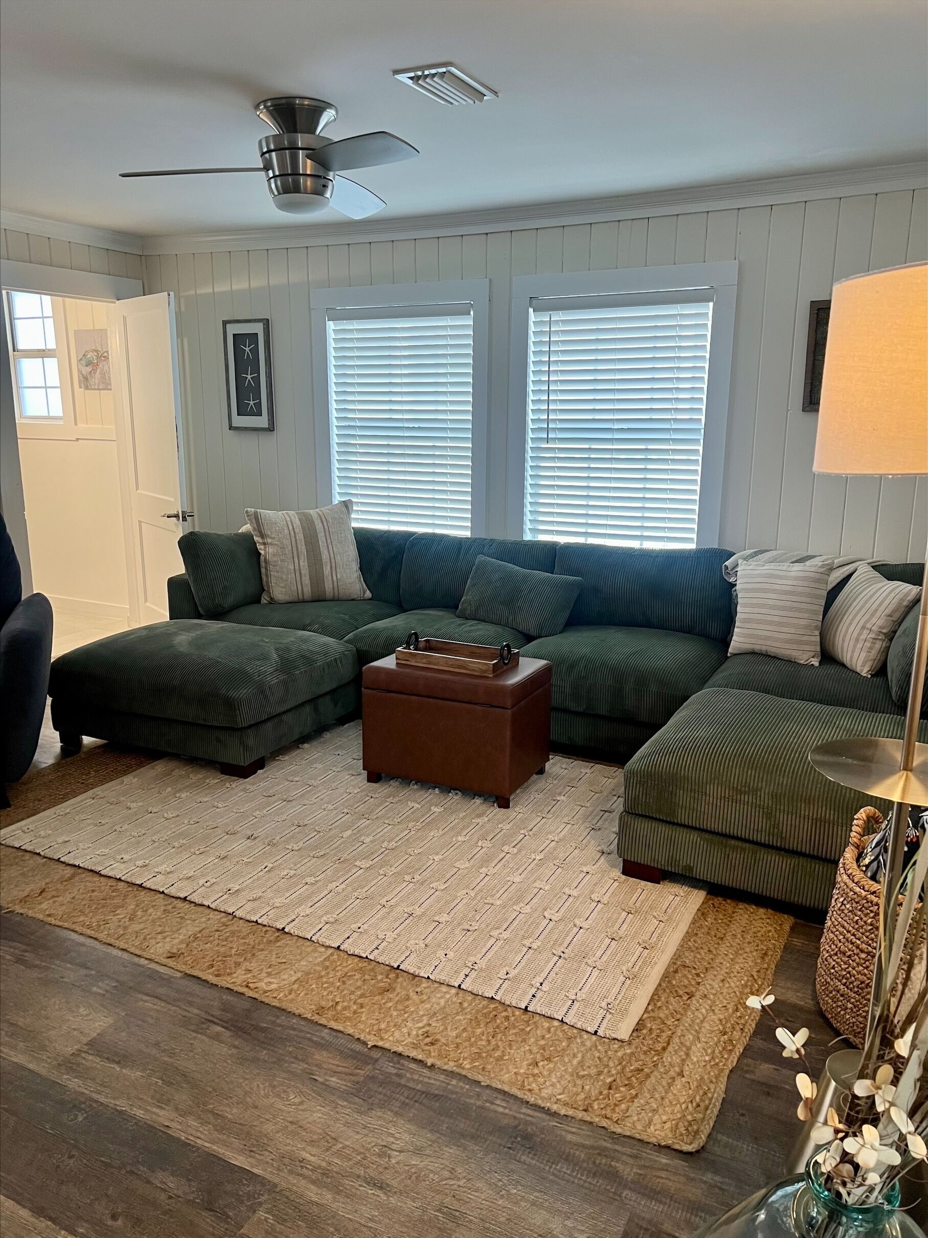 A living room with a sectional sofa, a wooden coffee table, and a floor lamp.