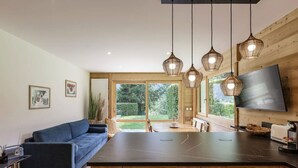 A modern kitchen with a large island, wooden cabinetry, and pendant lighting. - Modern 2BR | MtBlanc View | Terrace | Brevent 3mn (Chamonix-Mont-Blanc)
