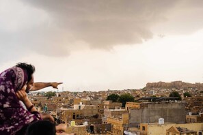Vista de uma área urbana densamente povoada com arquitetura tradicional e uma colina imponente ao fundo.