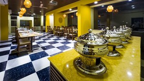 Un restaurante con suelo a cuadros, paredes amarillas y varias mesas con sillas.