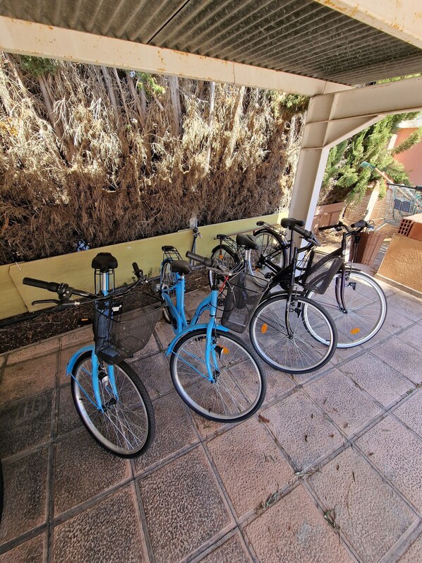 Bicycles are stored in this covered outdoor area adjacent to a textured wall.