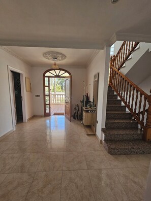 Stunning interior space with a grand staircase and arched doorway leading to a balcony.