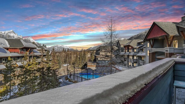 A mountain resort with snow-covered roofs, a pool, and a view of snow-capped mountains. - Penthouse•King Beds•Pool•BikeStorage (Canmore)