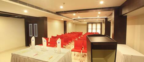 A conference room with a round table, red chairs, and a white tablecloth.