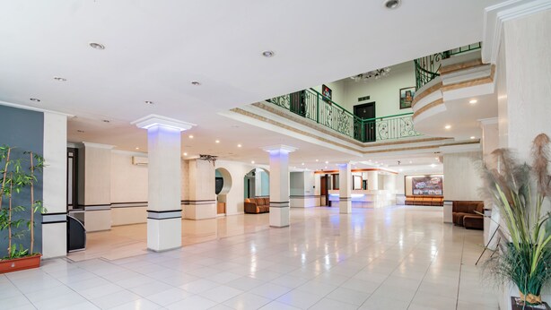 A spacious lobby with a high ceiling, multiple seating areas, and a staircase leading to an upper level.