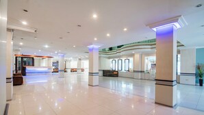 A spacious lobby with a reception desk, seating area, and a staircase leading to an upper level.