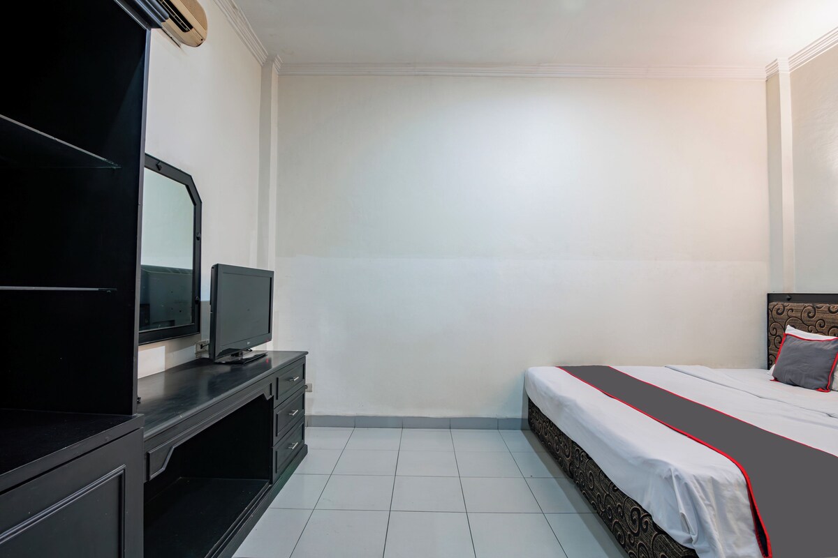 Un dormitorio con una cama, un televisor sobre un mueble bajo y un aparador.