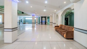 A spacious lobby with a modern design, featuring a central seating area and a staircase leading to an upper level.