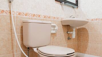 A standard bathroom with a toilet, sink, and a mirror above the sink.