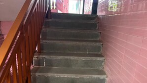 A staircase with wooden handrails and a pink wall. - Abbi S Nest (Calangute)